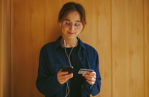 giovane donna che utilizza una carta di credito e un telefono cellulare per lo shopping online elaborazione di foto d'epoca