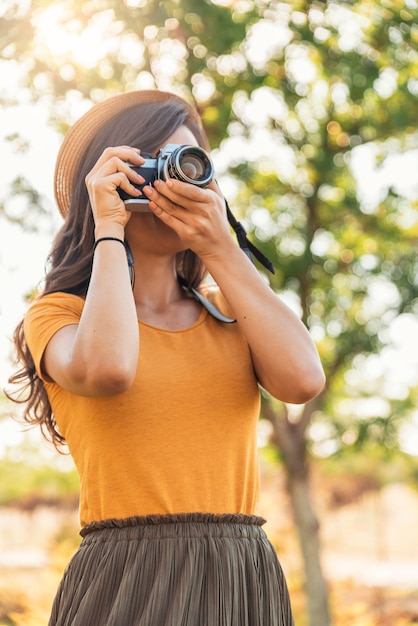 Giovane donna che utilizza una fotocamera per scattare foto al parco.