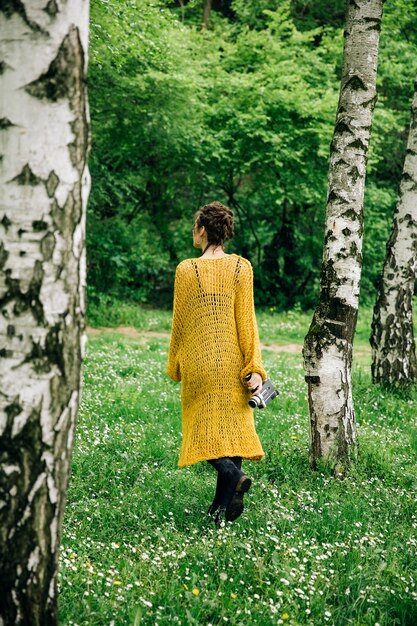 Giovane donna che utilizza una macchina fotografica del cinema dell&#39;annata in un parco