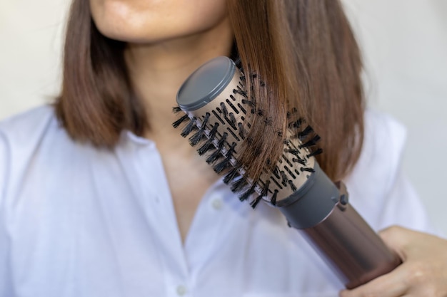 giovane donna che utilizza una moderna spazzola per capelli rotativa per acconciare i capelli ragazza sorridente si chiuda al rallentatore