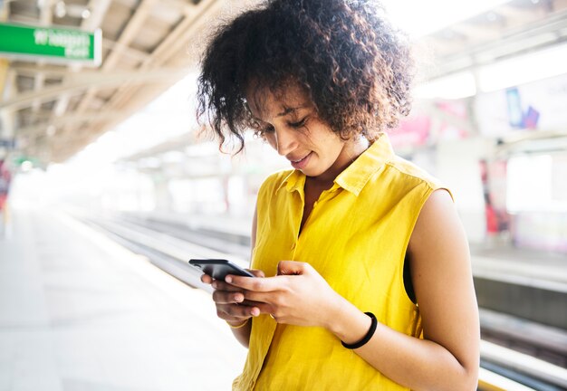 Giovane donna che utilizza uno smartphone sulla stazione della metropolitana