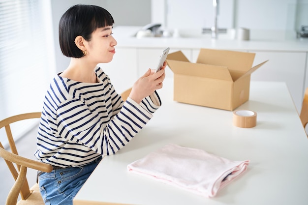 Giovane donna che vende vestiti con lo smartphone