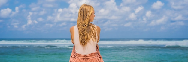 Giovane donna che viaggia sulla straordinaria spiaggia di Melasti con acqua turchese, isola di Bali Indonesia BANNER, FORMATO LUNGO