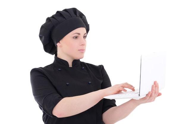 Giovane donna chef in uniforme nera con laptop isolato su sfondo bianco