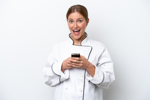 Giovane donna chef isolata su sfondo bianco sorpresa e l'invio di un messaggio