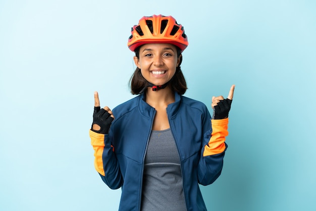 Giovane donna ciclista isolata su sfondo blu rivolto verso l'alto una grande idea