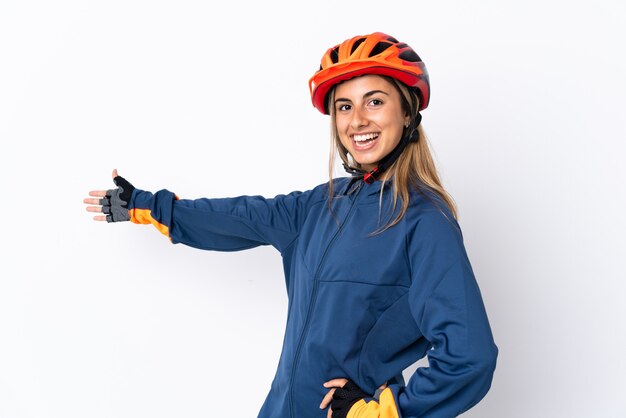 Giovane donna ciclista ispanica isolata sulla parete bianca che estende le mani a lato per invitare a venire