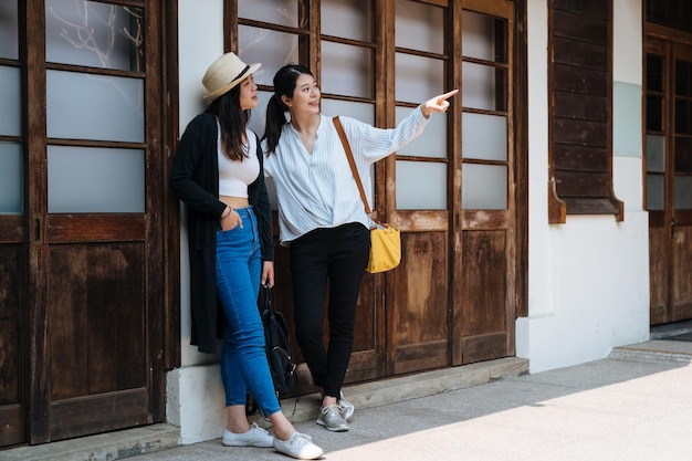 Giovane donna cinese asiatica attraente che indica il dito che mostra amico con il cielo soleggiato blu. Un ritratto di due bellissime ragazze viaggiano in estate a Tokyo in Giappone. le sorelle a figura intera si godono la vista all'aperto