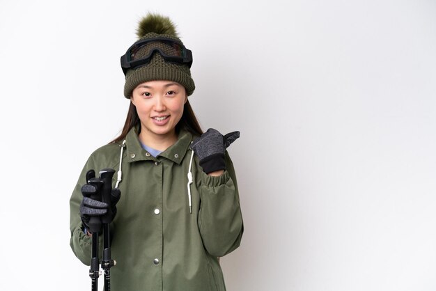 Giovane donna cinese che indossa una giacca invernale isolata su sfondo bianco che indica il lato per presentare un prodotto