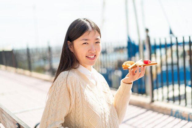 Giovane donna cinese che tiene sashimi all'aperto che sorride molto