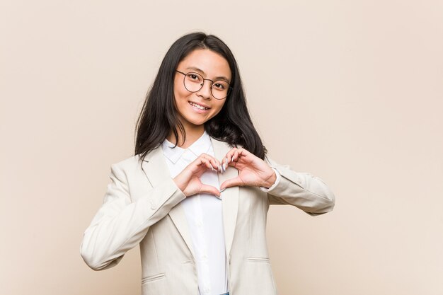 Giovane donna cinese di affari che sorride e che mostra una figura del cuore con le mani.