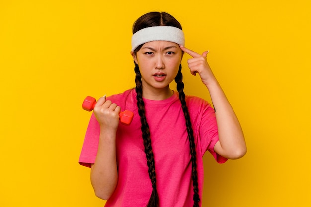 Giovane donna cinese di sport isolata su colore giallo che mostra un gesto di delusione con l'indice.