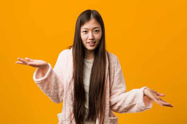 Giovane donna cinese in pigiama che dubita tra due opzioni.