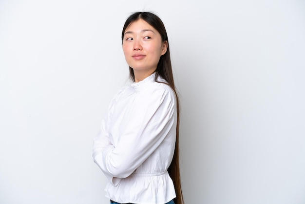 Giovane donna cinese isolata su sfondo bianco con le braccia incrociate e felice