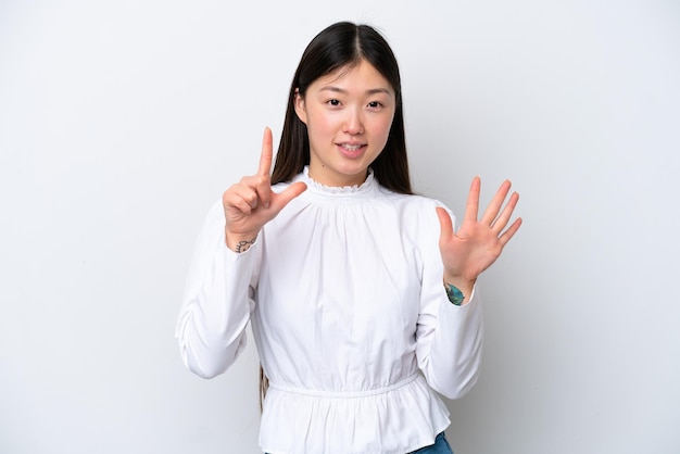 Giovane donna cinese isolata su sfondo bianco contando sette con le dita
