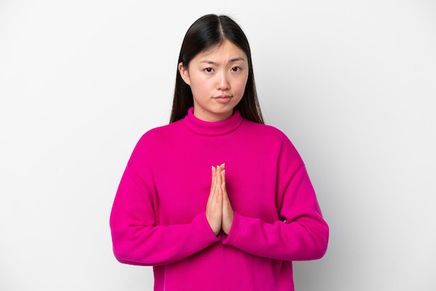 Giovane donna cinese isolata su sfondo bianco tiene insieme il palmo La persona chiede qualcosa