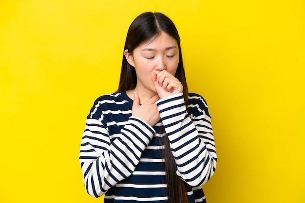 Giovane donna cinese isolata su sfondo giallo che tossisce molto