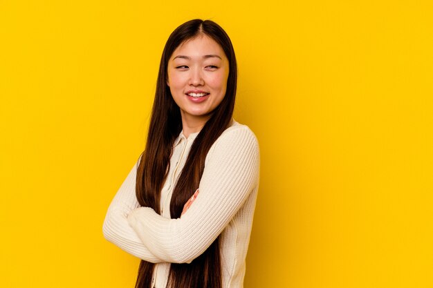 Giovane donna cinese isolata su sfondo giallo ridendo e divertendosi.