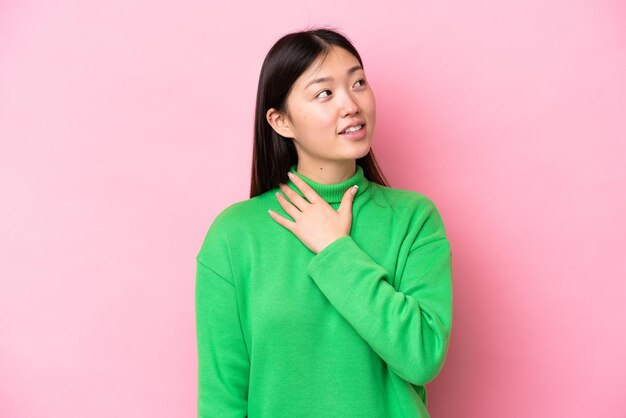 Giovane donna cinese isolata su sfondo rosa alzando lo sguardo sorridendo