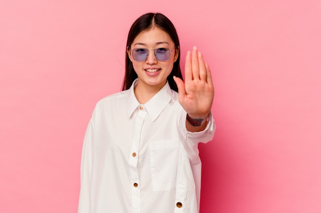 Giovane donna cinese isolata su sfondo rosa sorridente allegro che mostra il numero cinque con le dita.
