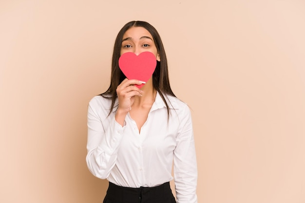 Giovane donna colombiana che tiene una carta del cuore per il giorno di biglietti di S. Valentino isolato