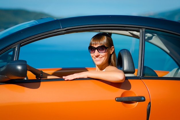 Giovane donna con auto sul lato mare