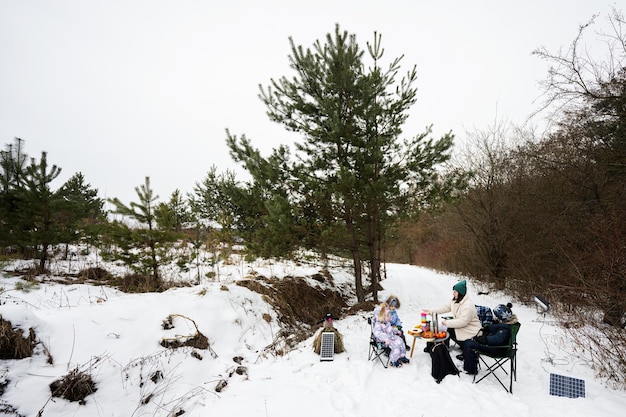 Giovane donna con bambini nella foresta invernale in un picnic Madre e tre bambini