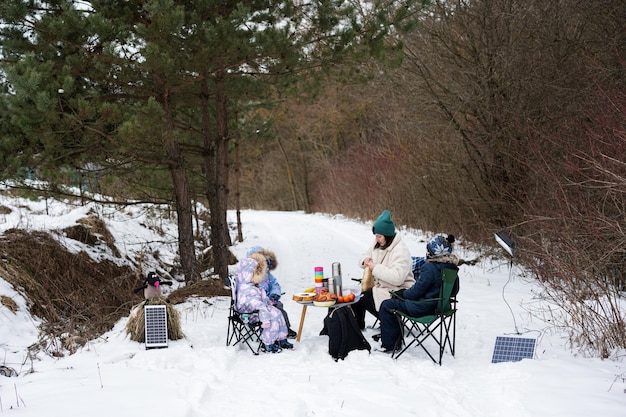 Giovane donna con bambini nella foresta invernale in un picnic Madre e tre bambini