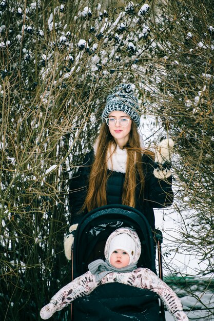 Giovane donna con bambino nel passeggino nel Bush in giornata invernale