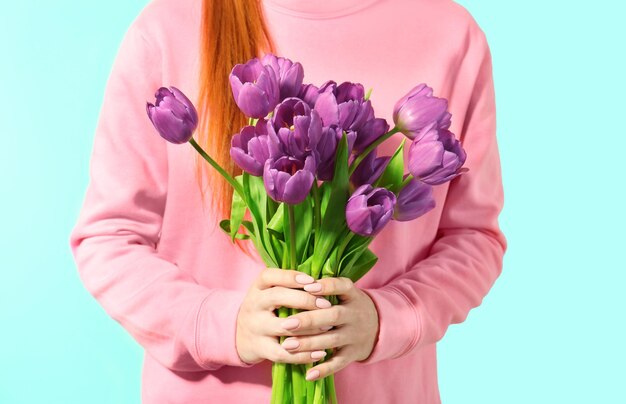 Giovane donna con bouquet di bei tulipani lilla su sfondo di colore chiaro primo piano