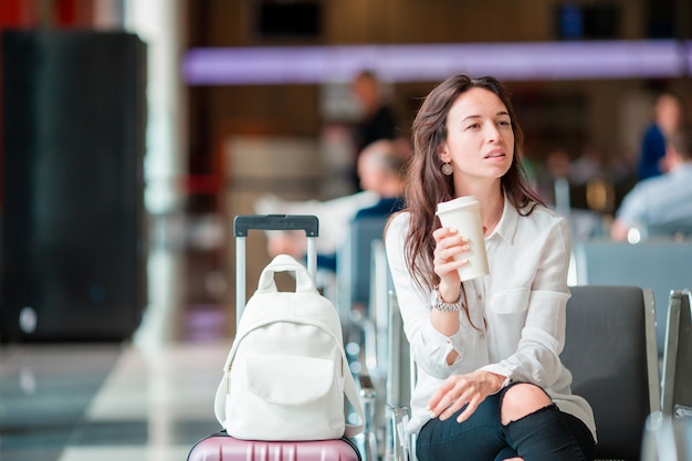 Giovane donna con caffè in un aeroporto in attesa di volo aereo.