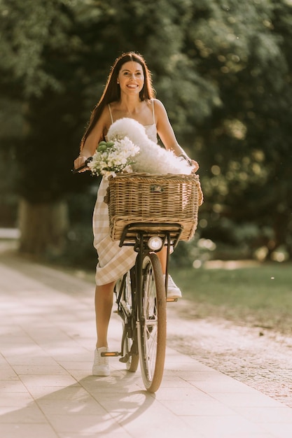 Giovane donna con cane bianco bichon frise nel cestino della bici elettrica