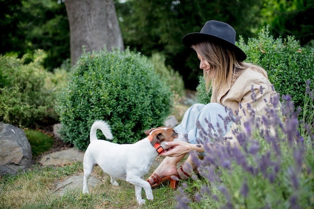 Giovane donna con cane seduto in un giardino