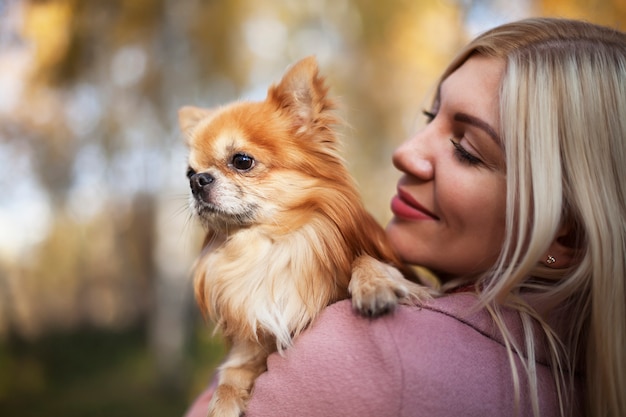 Giovane donna con cane tra le braccia sullo sfondo della bellissima natura