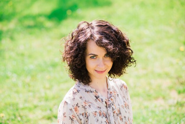 Giovane donna con capelli lunghi ricci in posa nel giardino fiorito primaverile