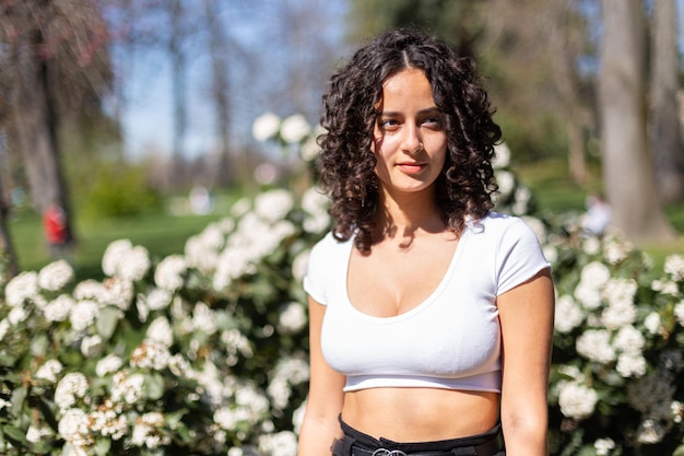 Giovane donna con capelli ricci nel parco godendosi il sole