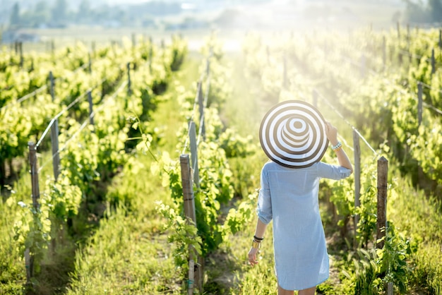 Giovane donna con cappello a strisce godendo di una splendida vista del tramonto sul vigneto nella regione di Bordeaux in Francia