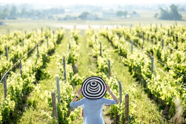 Giovane donna con cappello a strisce godendo di una splendida vista del tramonto sul vigneto nella regione di Bordeaux in Francia