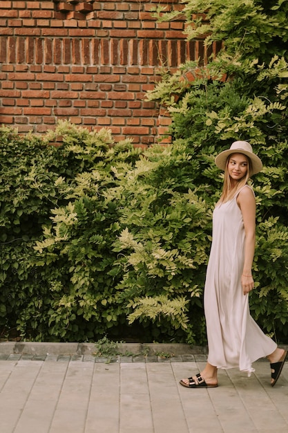 Giovane donna con cappello che cammina nel giardino del resort