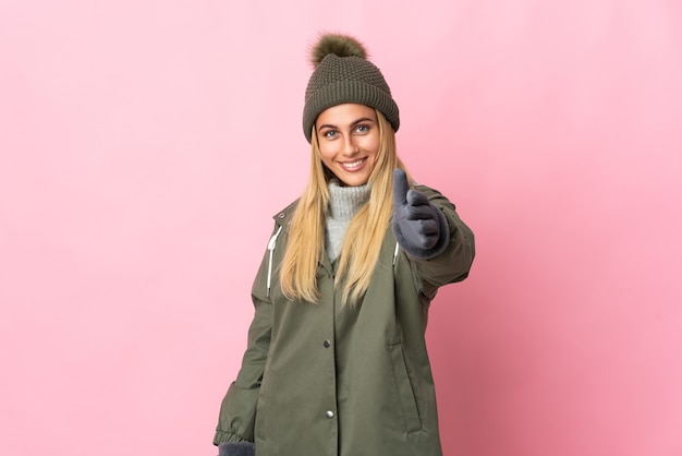 Giovane donna con cappello invernale in rosa stringe la mano per chiudere un buon affare