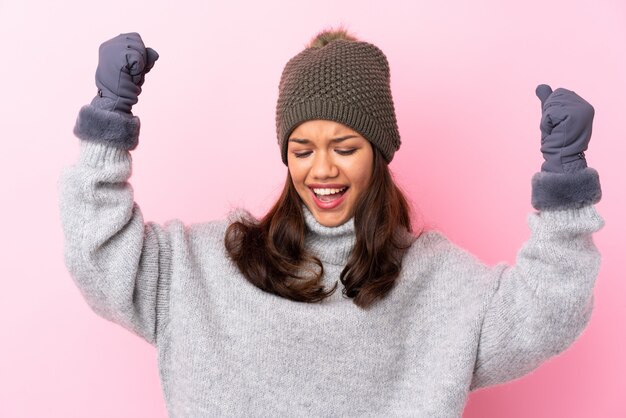 giovane donna con cappello invernale su muro isolato