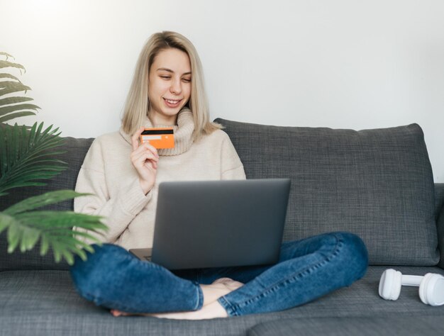 Giovane donna con carta di credito e computer portatile