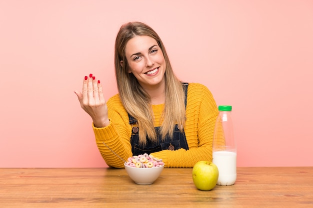 Giovane donna con ciotola di cereali che invita a venire