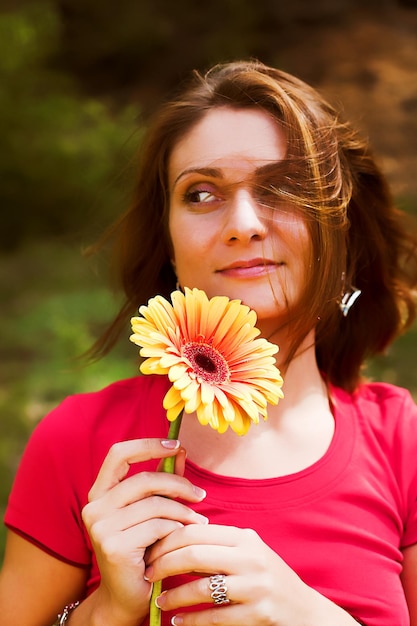 Giovane donna con fiori all'aperto