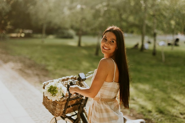 Giovane donna con fiori nel cestino della bici elettrica