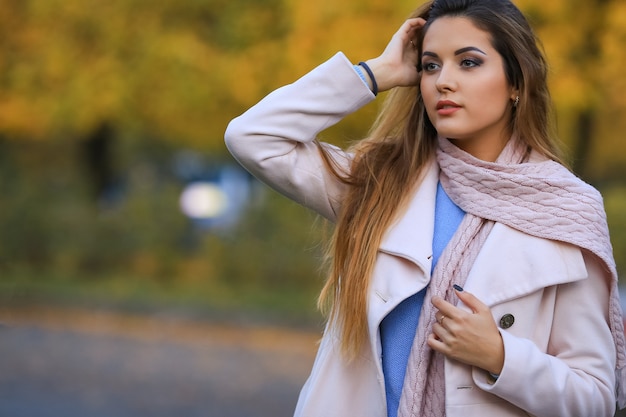 Giovane donna con foglie autunnali in mano e fondo del giardino di acero giallo autunno