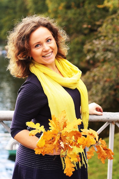 Giovane donna con foglie di autunno nel parco