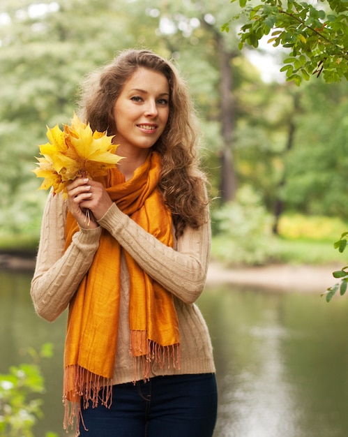 Giovane donna con foglie di autunno nel parco