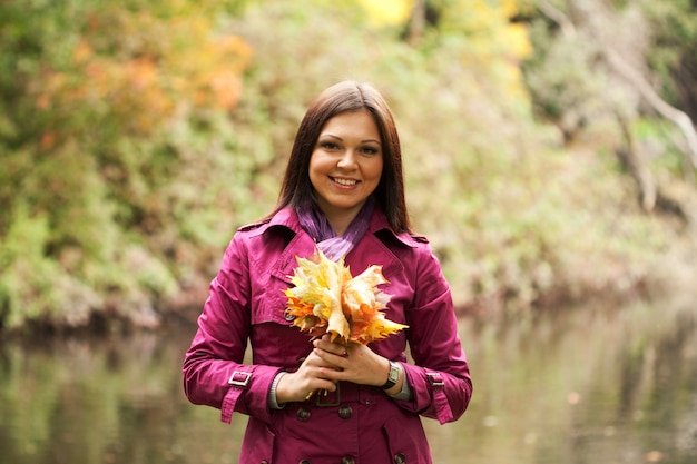 Giovane donna con foglie di autunno nel parco