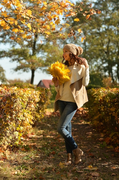 Giovane donna con foglie in posa in autunno park